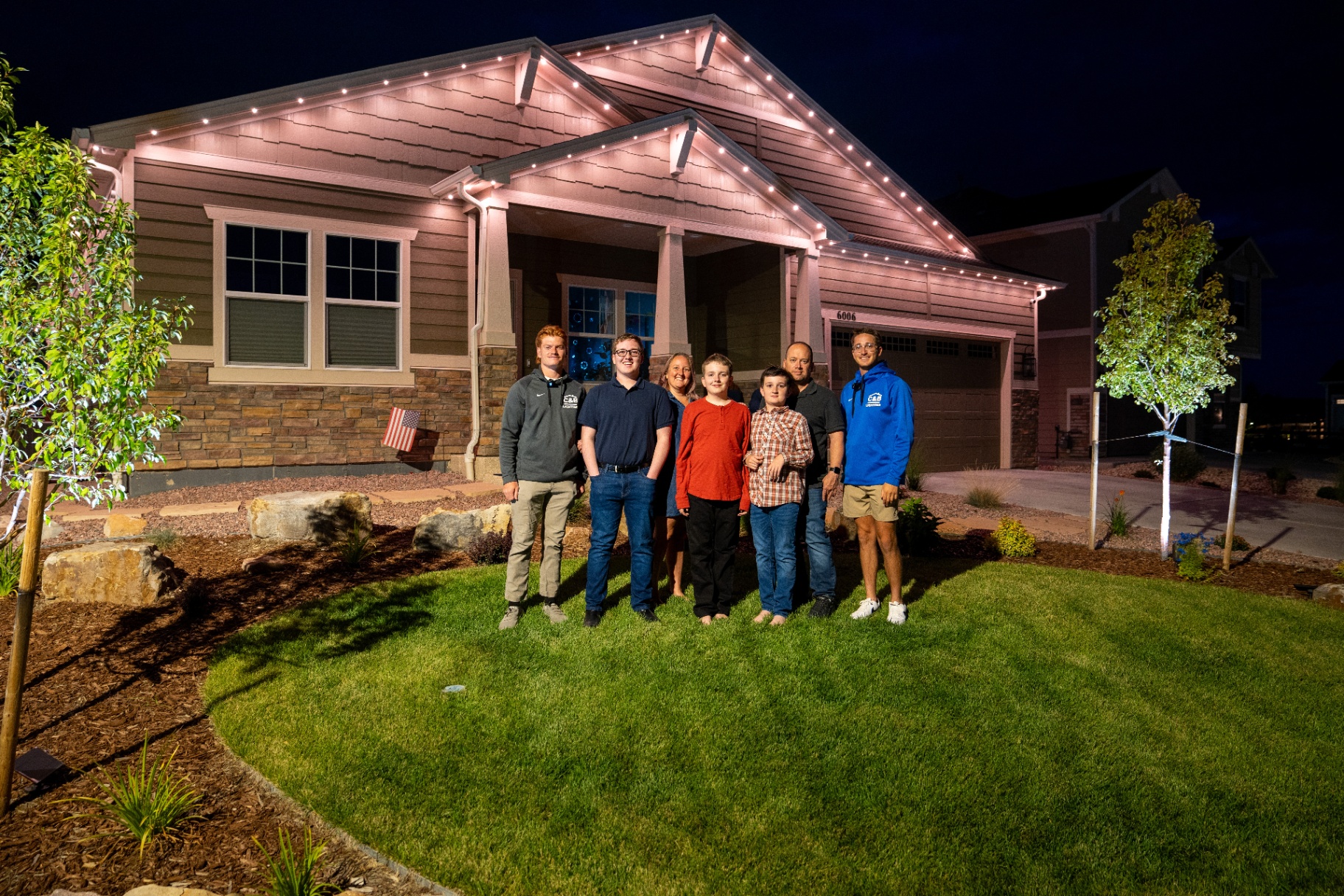 Family outside their Bethlehem home illuminated by permanent outdoor lighting at night